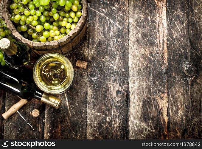 White wine with a bucket of green grapes. On a wooden background.. White wine with a bucket of green grapes.