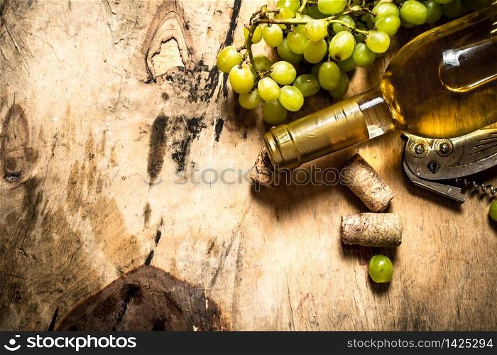 White wine with a bunch of grapes. On wooden background.. White wine with a bunch of grapes.