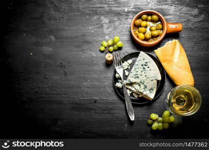White wine with a flavorful cheese and tasty olives.. White wine with flavorful cheese and tasty olives.