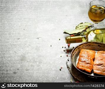 White wine with a grilled salmon fillet. On the stone table.. White wine with a grilled salmon fillet.