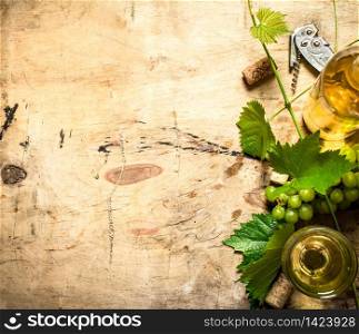 White wine with a vine . On wooden background.. White wine with a vine .
