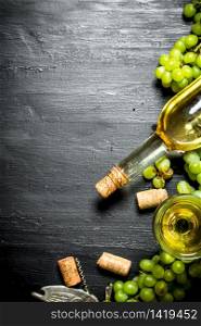 White wine with branches of grapes. On a black wooden background.. White wine with branches of grapes.