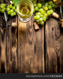 White wine with branches of white grapes. On a wooden table.. White wine with branches grapes.