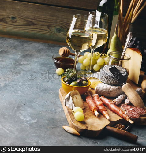 White wine with charcuterie assortment on the stone background. Wine and snack set