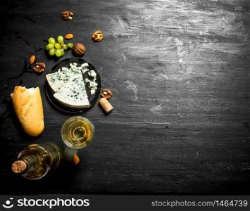 White wine with French blue cheese and nuts. On black wooden board. White wine with French blue cheese and nuts.
