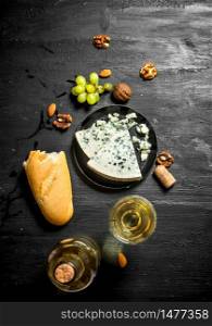 White wine with French blue cheese and nuts. On black wooden board. White wine with French blue cheese and nuts.