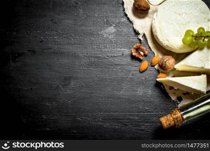 White wine with goat cheese, grapes and nuts. On a black wooden background. White wine with goat cheese, grapes and nuts.