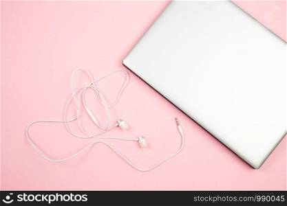 white wired headphones and laptop on pink isolated background. top view. flat lay. mockup