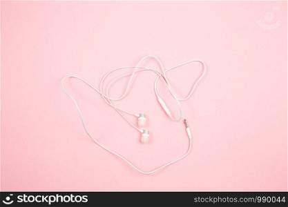 white wired headphones on pink isolated background. top view. flat lay. mockup