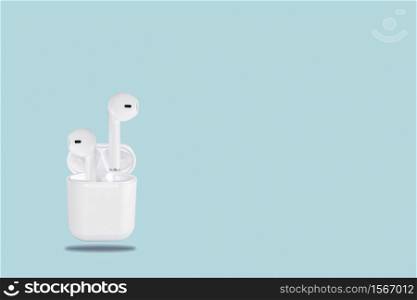 White wireless bluetooth earphones and storage charging case on blue background