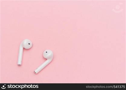 White wireless Bluetooth headphones on pink paper background. Template for text or your design. Flat lay Top view Copy space.. White wireless Bluetooth headphones on pink paper background. Template for text or your design. Flat lay Top view Copy space