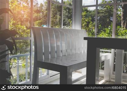 white wood bench and table beside glass door with garden view