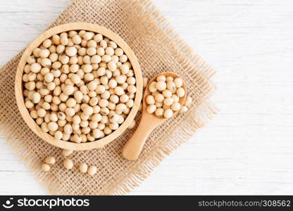 White wood floor with wooden cup with soybean, top view and copyspace, soybeans in wooden bowl with wooden spoon on table wooden