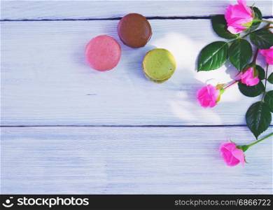 White wooden background with cakes and a bouquet of pink roses