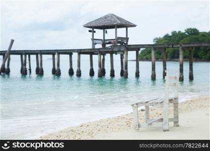 White wooden beach chair. On the beach. Behind the bridge into the sea.