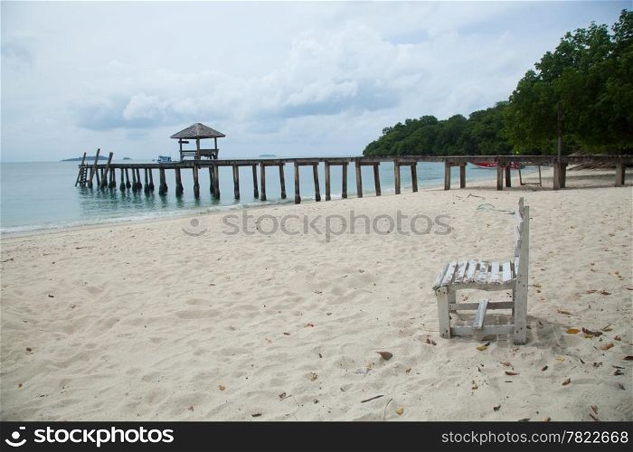 White wooden beach chair. On the beach. Behind the bridge into the sea.