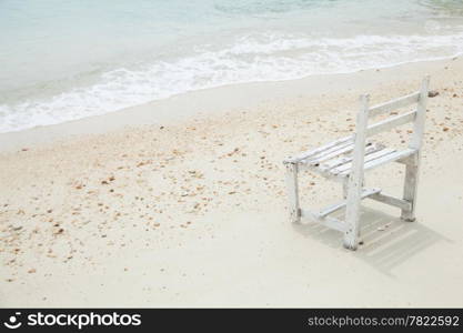 White wooden chair. Placed on the sand beach by the sea.