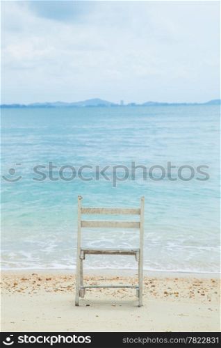 White wooden chair. Placed on the sand beach by the sea.
