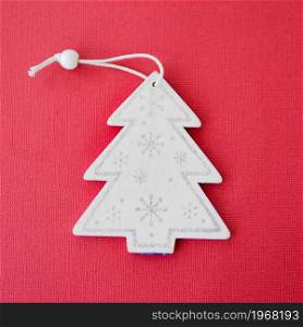white wooden figurine of a Christmas tree on a red paper background.