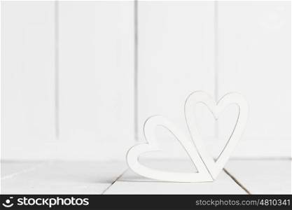 White wooden hearts. Two decorative white hearts on wooden background
