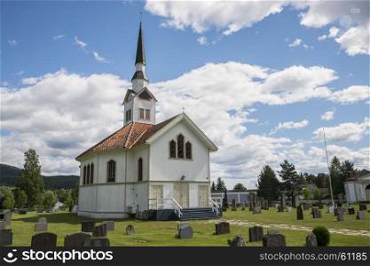 white wooden stave church near Leira in Norway with cemetery