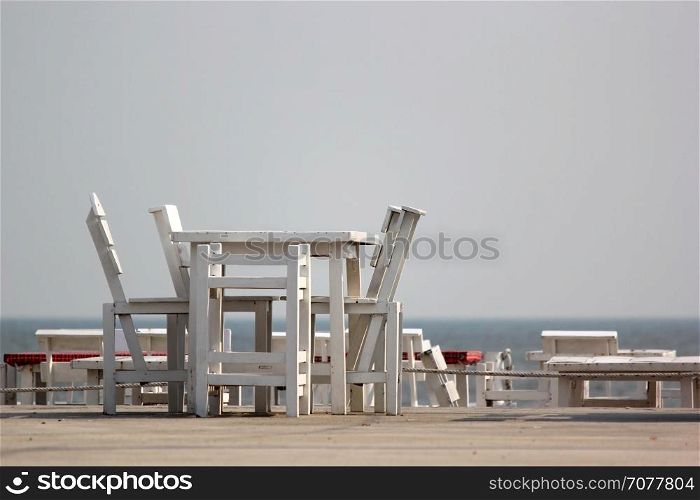 white wooden tables and chairs on terrace of beach restaurant