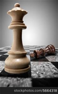White wooden victorious queen standing on a chessboard against the background of a crushed defeated king.