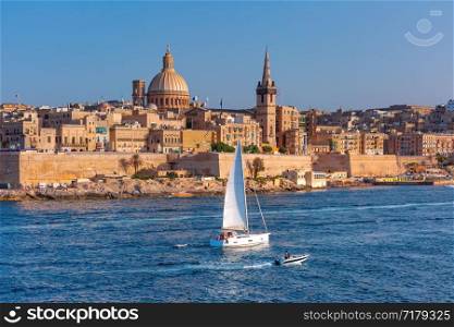 White yacht and Old town of Valletta with churches of Our Lady of Mount Carmel and St. Paul&rsquo;s Anglican Pro-Cathedral, Valletta, Capital city of Malta. Valletta Skyline from Sliema at sunset, Malta