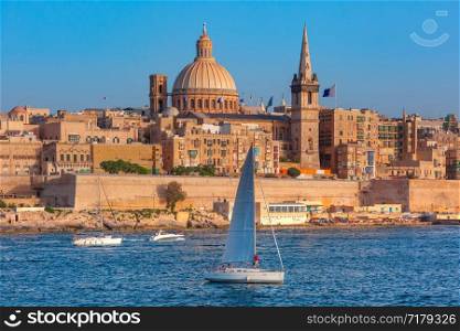 White yacht and Old town of Valletta with churches of Our Lady of Mount Carmel and St. Paul&rsquo;s Anglican Pro-Cathedral, Valletta, Capital city of Malta. Valletta Skyline from Sliema at sunset, Malta
