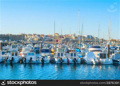 White yachts and motor boats moored by pier in marina, Peniche, Portugal