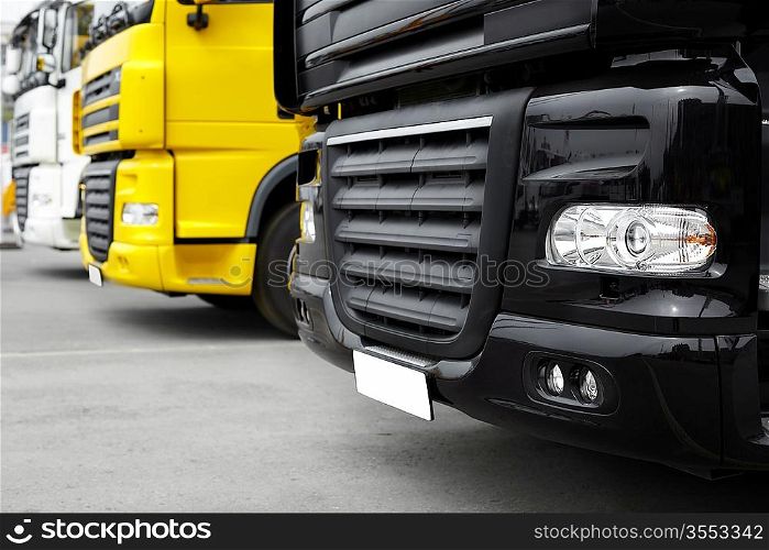 white ,yellow and black trucks, selective focus on nearest part