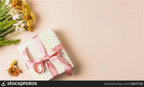 white yellow flower bouquet near wrapped present box peach surface. Resolution and high quality beautiful photo. white yellow flower bouquet near wrapped present box peach surface. High quality and resolution beautiful photo concept