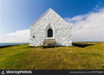 Whitewashed front of church in the sea Eglwys Cwyfan. Aberffraw, Anglesey, Wales, United Kingdom, landscape, wide angle.