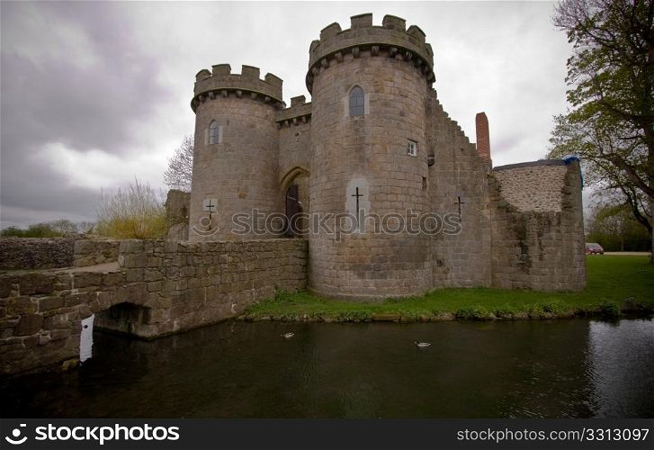 Whittington Castle in Shropshire reflected in moat with cloudy sky