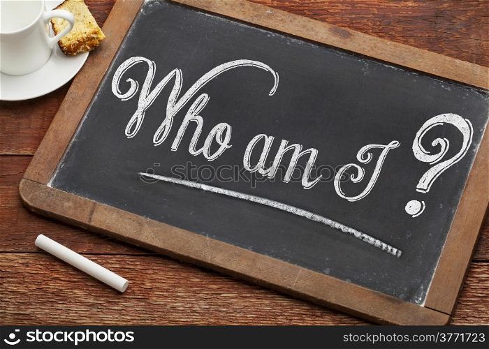 Who am I ? A philosophical question on a vintage blackboard with white chalk with a cup of coffee