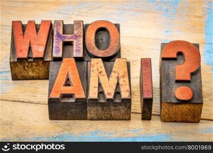 Who am I - a philosophical question spelled in vintage letterpress wood type printing blocks against grunge, painted wood