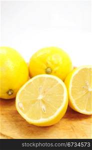 Whole and half lemons on wooden board