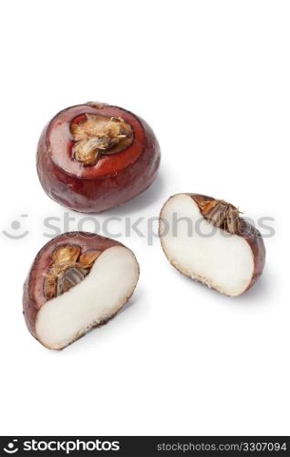 Whole and half water chestnuts on white background