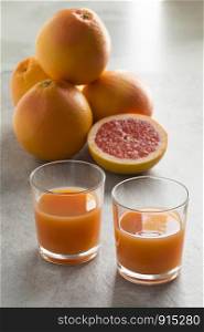 Whole and halved fresh juicy red grapefruit and glasses with juice