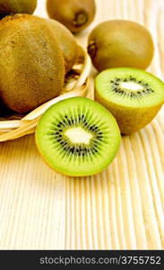 Whole and halves kiwi in a wicker plate and on the background of wooden boards