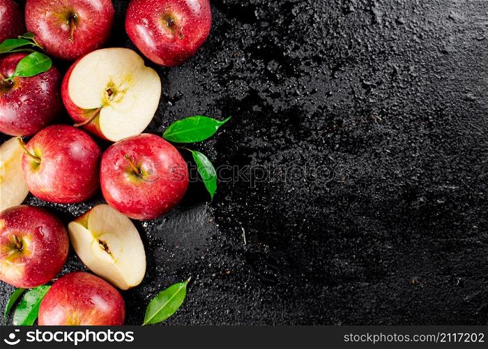 Whole and pieces of red apple with leaves. On a black background. High quality photo. Whole and pieces of red apple with leaves.
