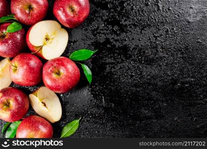 Whole and pieces of red apple with leaves. On a black background. High quality photo. Whole and pieces of red apple with leaves.