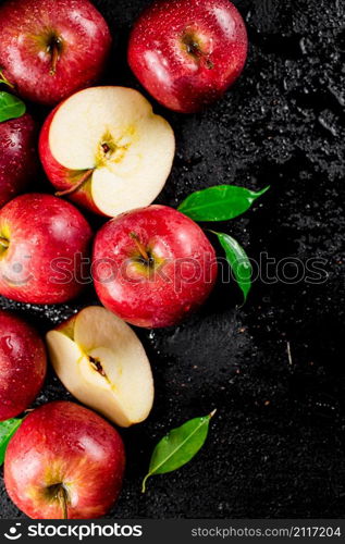 Whole and pieces of red apple with leaves. On a black background. High quality photo. Whole and pieces of red apple with leaves.