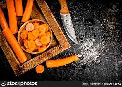 Whole and sliced carrots on a wooden tray. On a black background. High quality photo. Whole and sliced carrots on a wooden tray.