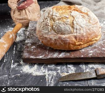 whole baked round white wheat bread on brown old wooden board