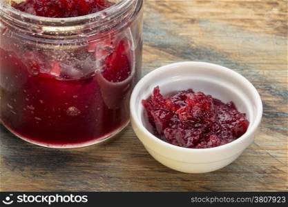 whole berry cranberry sauce - glass jar and small ceramic bowl on a grunge wood