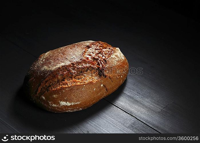Whole black bread on table