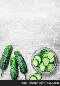 Whole cucumbers and cucumber slices in the bowl. On white rustic background. Whole cucumbers and cucumber slices in the bowl.