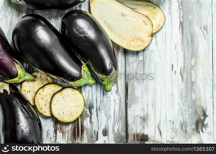 Whole eggplants and slice of eggplant. On white wooden background. Whole eggplants and slice of eggplant.