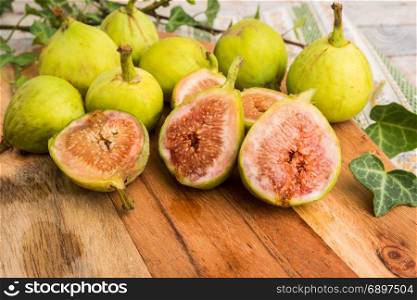 Whole figs in wicker basket on top of a rustic wooden table.